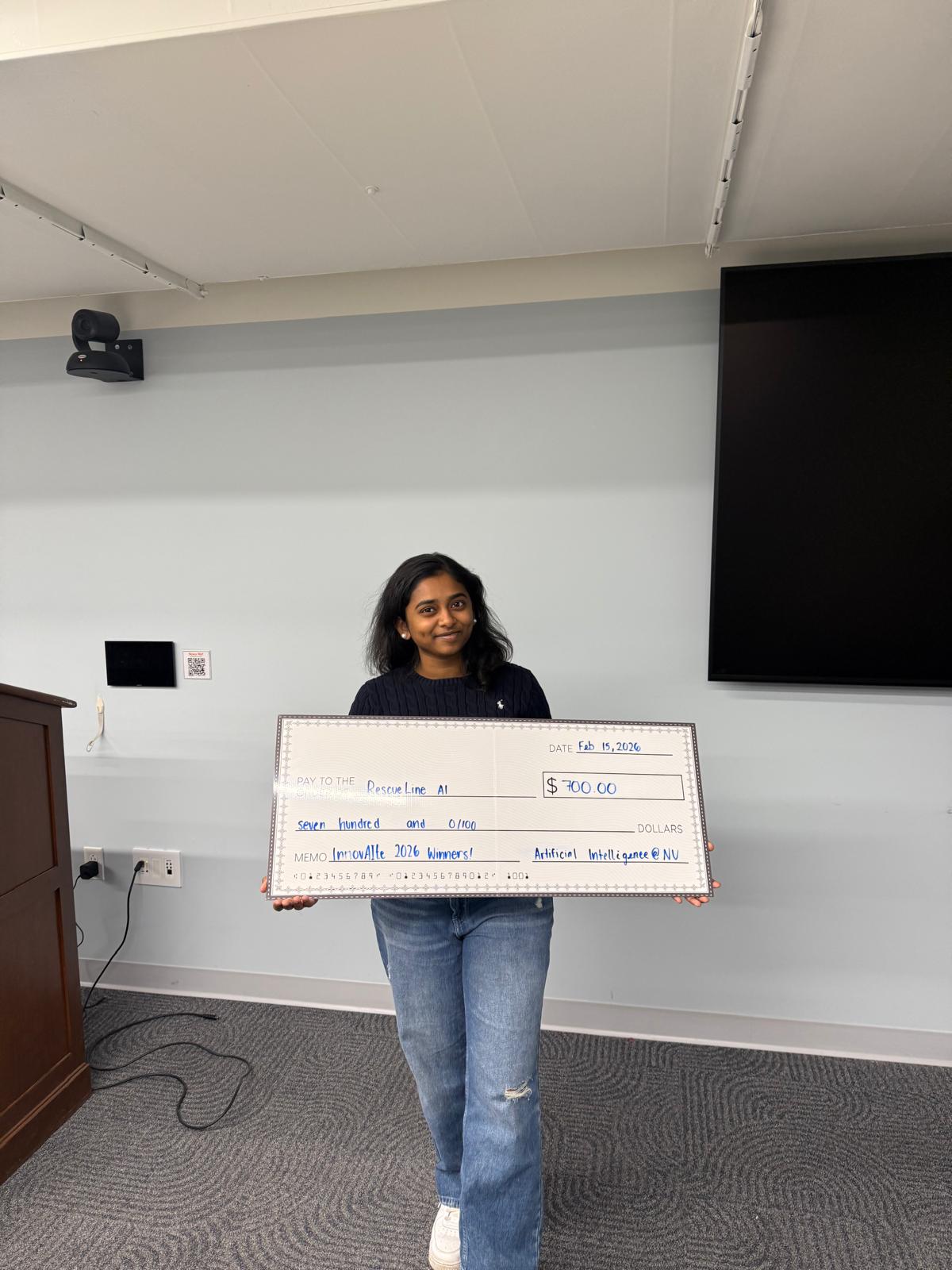 Pavithra holding $700 check at InnovAIte 2026 hackathon win